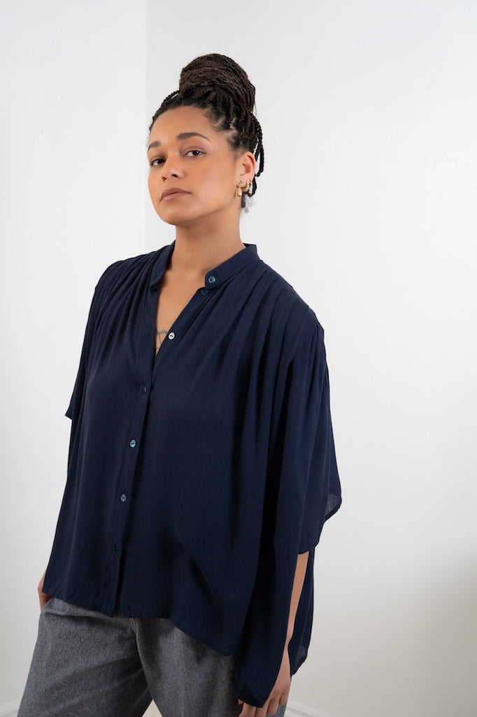 Blouse Marion bleue plissée – vue trois quarts, patte de boutonnage, col officier, oversize, boutons nacres, fabrication main Française, tissu bleu nuit fluide issu de stock dormant