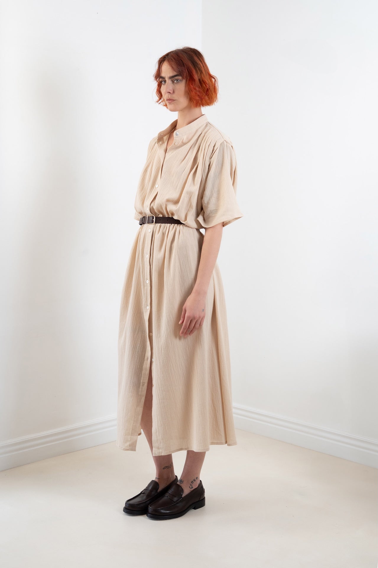 Maxi dress Robe Marine plissée oversize  couleur sable 100% coton, col officier, boutons nacres, portée ceinturée, vue trois quart – Onarch